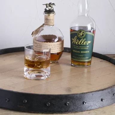 Barrel lazy susan with bottles of bourbon on it and whiskey glass