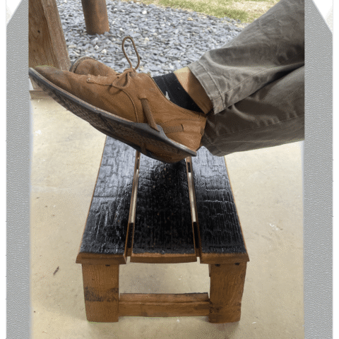 Barrel stave footrest with someone's feet resting on it